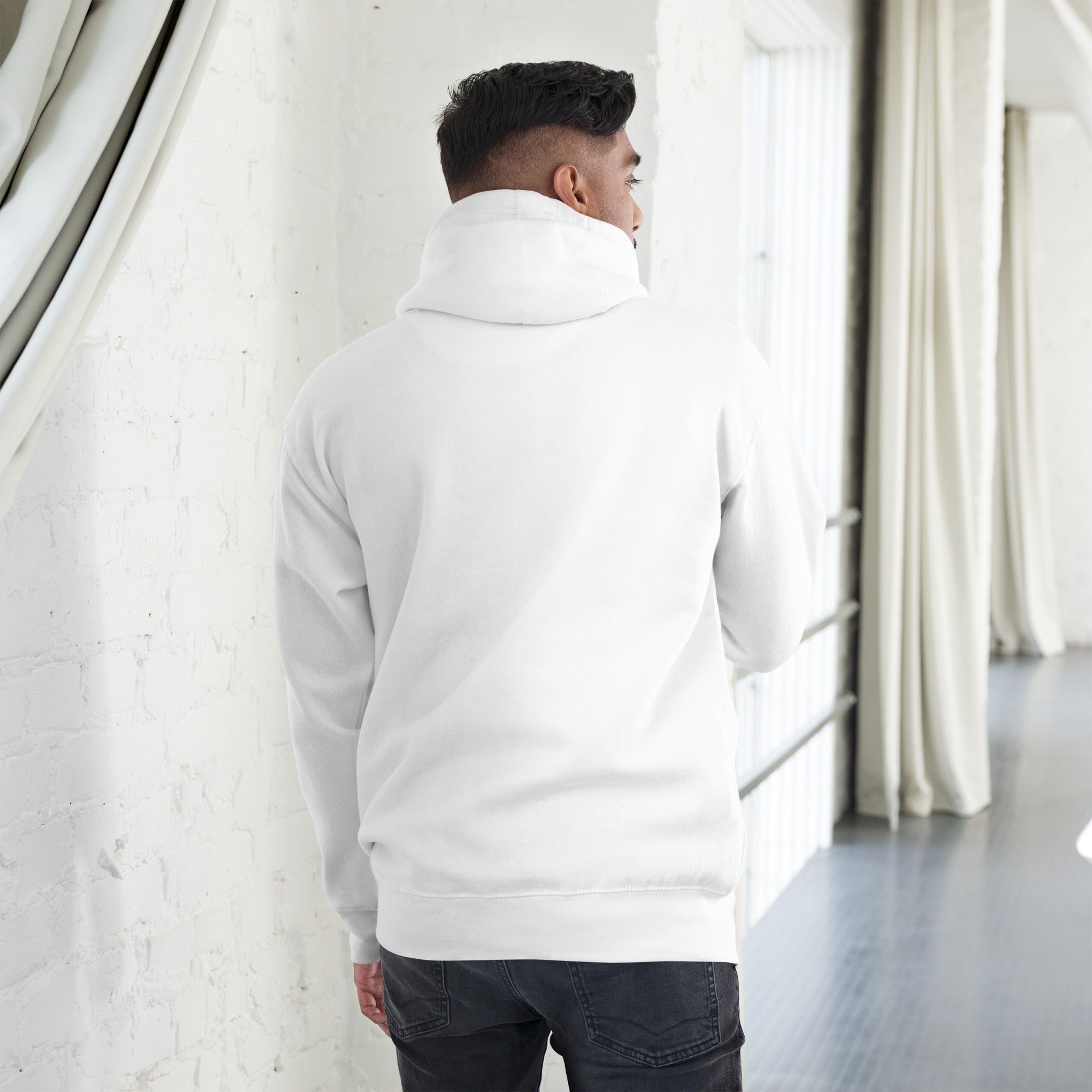 Man wearing a white unisex hoodie, showcasing the back design in a modern indoor setting.