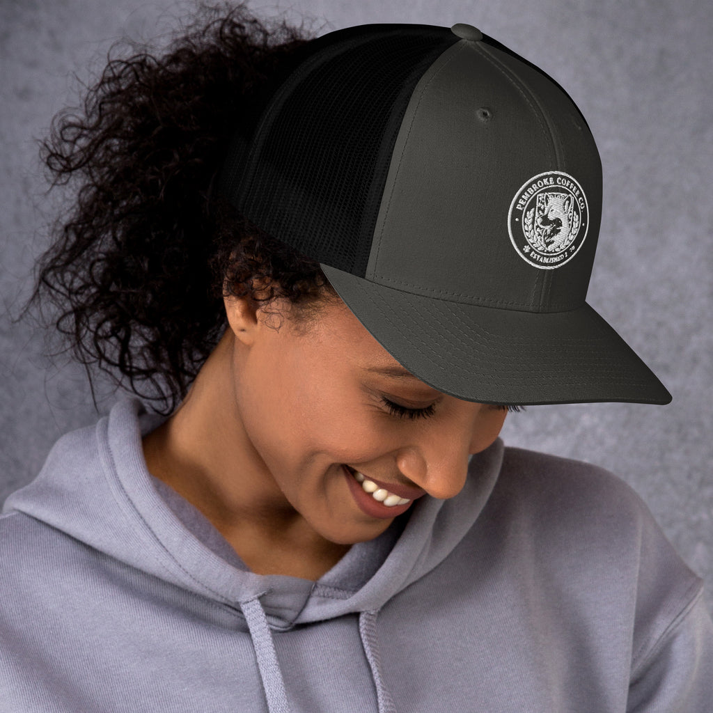 Trucker Cap worn by a smiling woman, showcasing a classic design with a mesh back and embroidered logo.