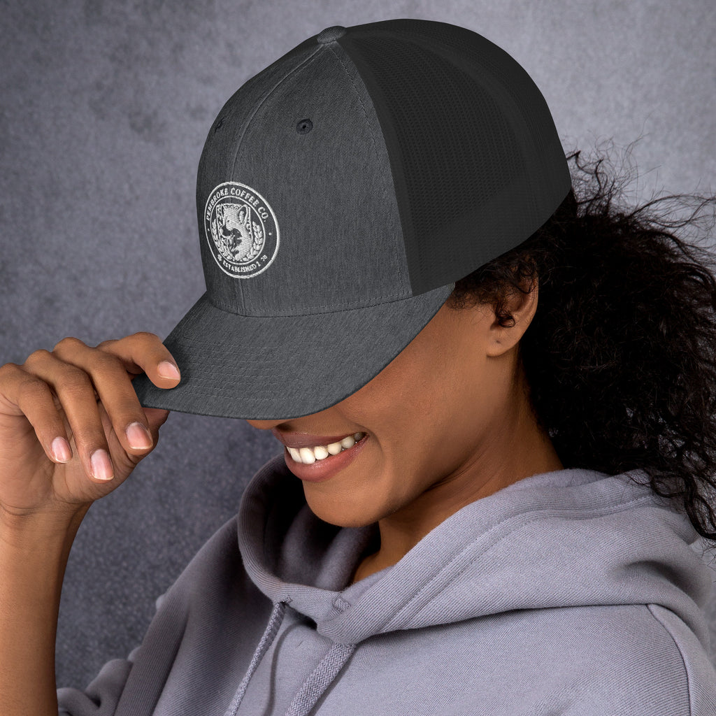 Smiling person wearing a Trucker Cap with logo, showcasing the comfortable and stylish design.