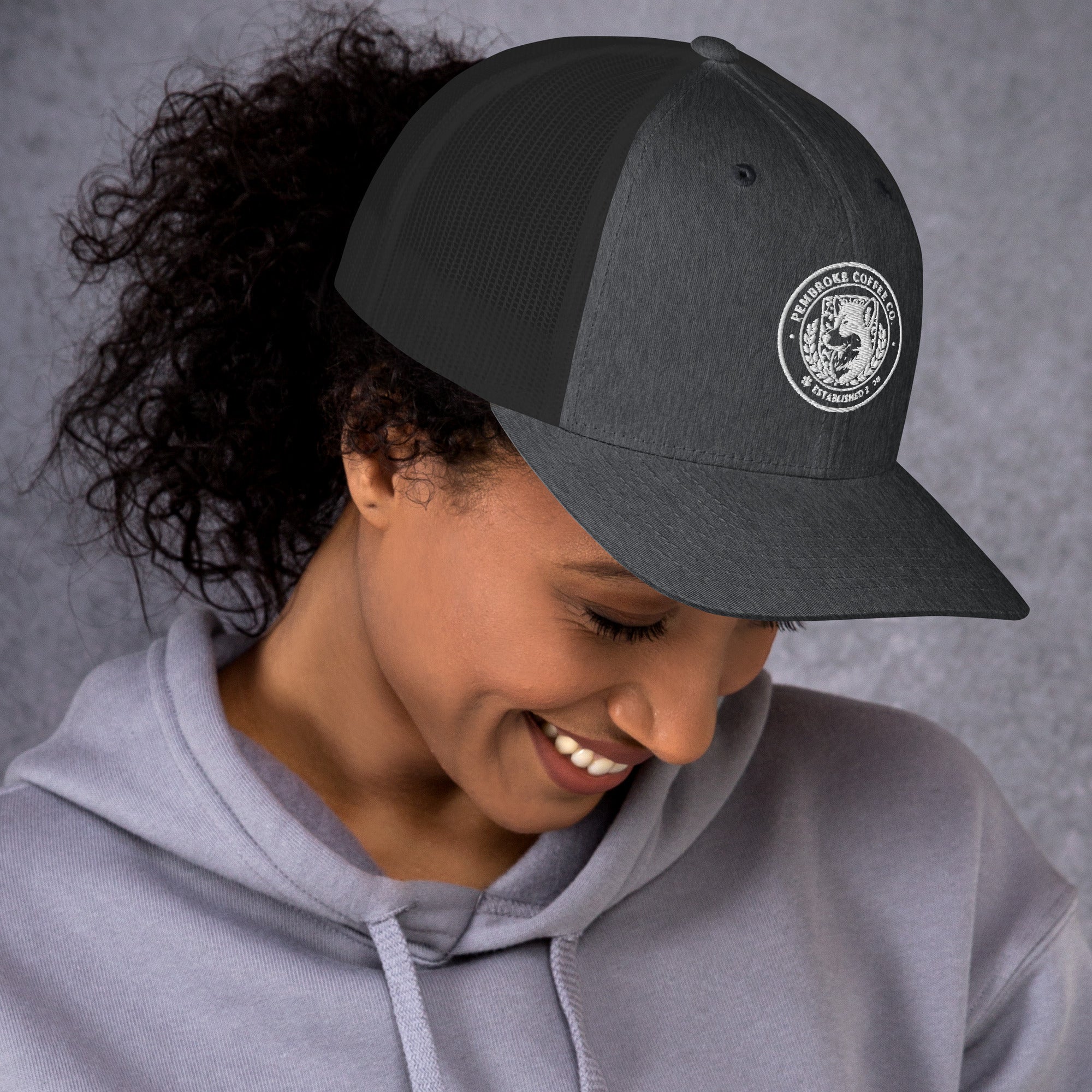 Trucker Cap featuring a structured six-panel design, mesh back, and a woman smiling while wearing it.
