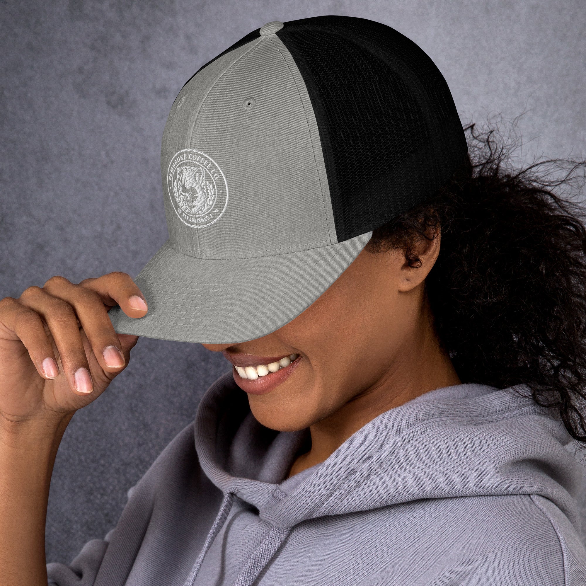 Woman smiling while wearing a stylish Trucker Cap with a mesh back and embroidered design.