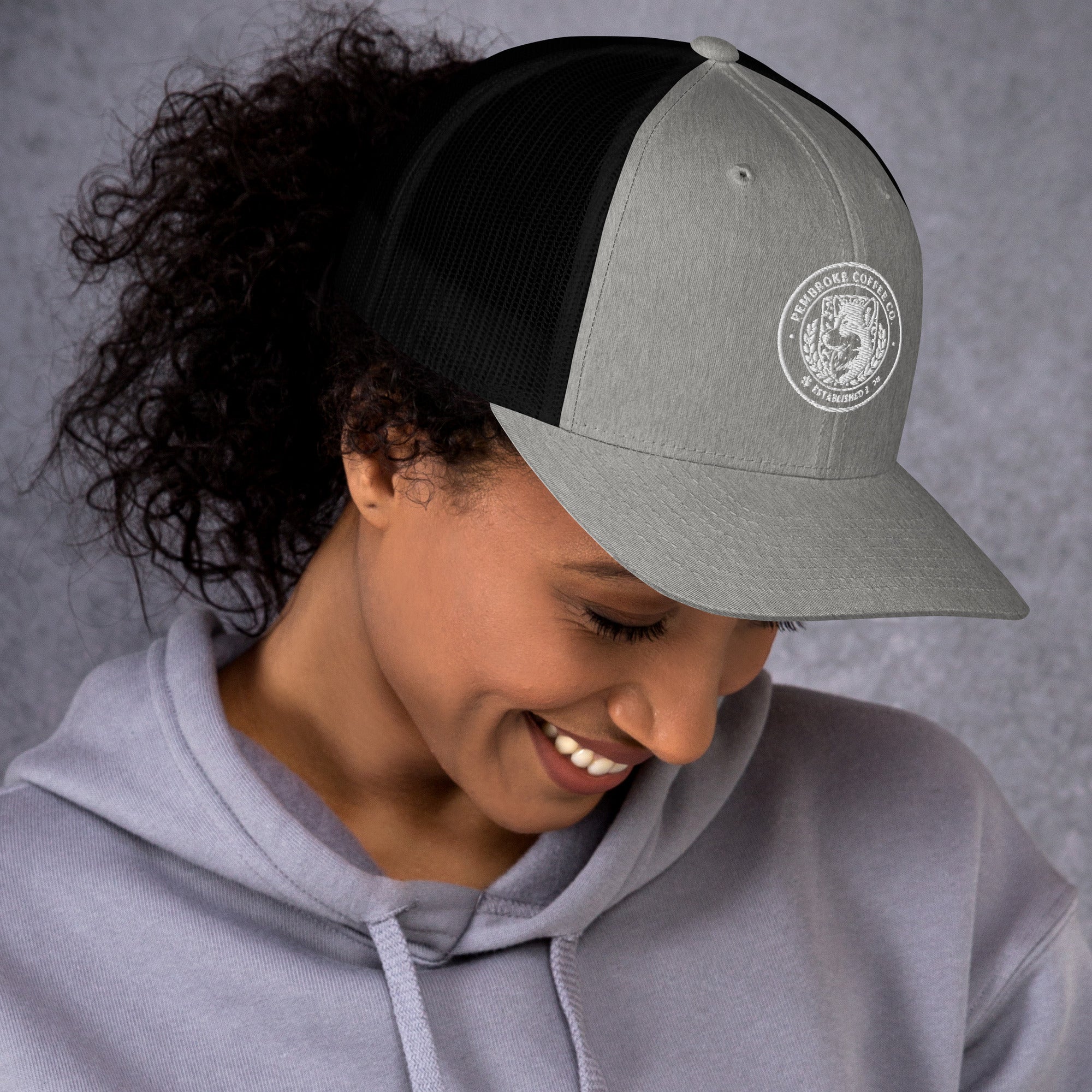 Woman wearing a Trucker Cap with a mesh back and embroidered design, smiling while enjoying the day.