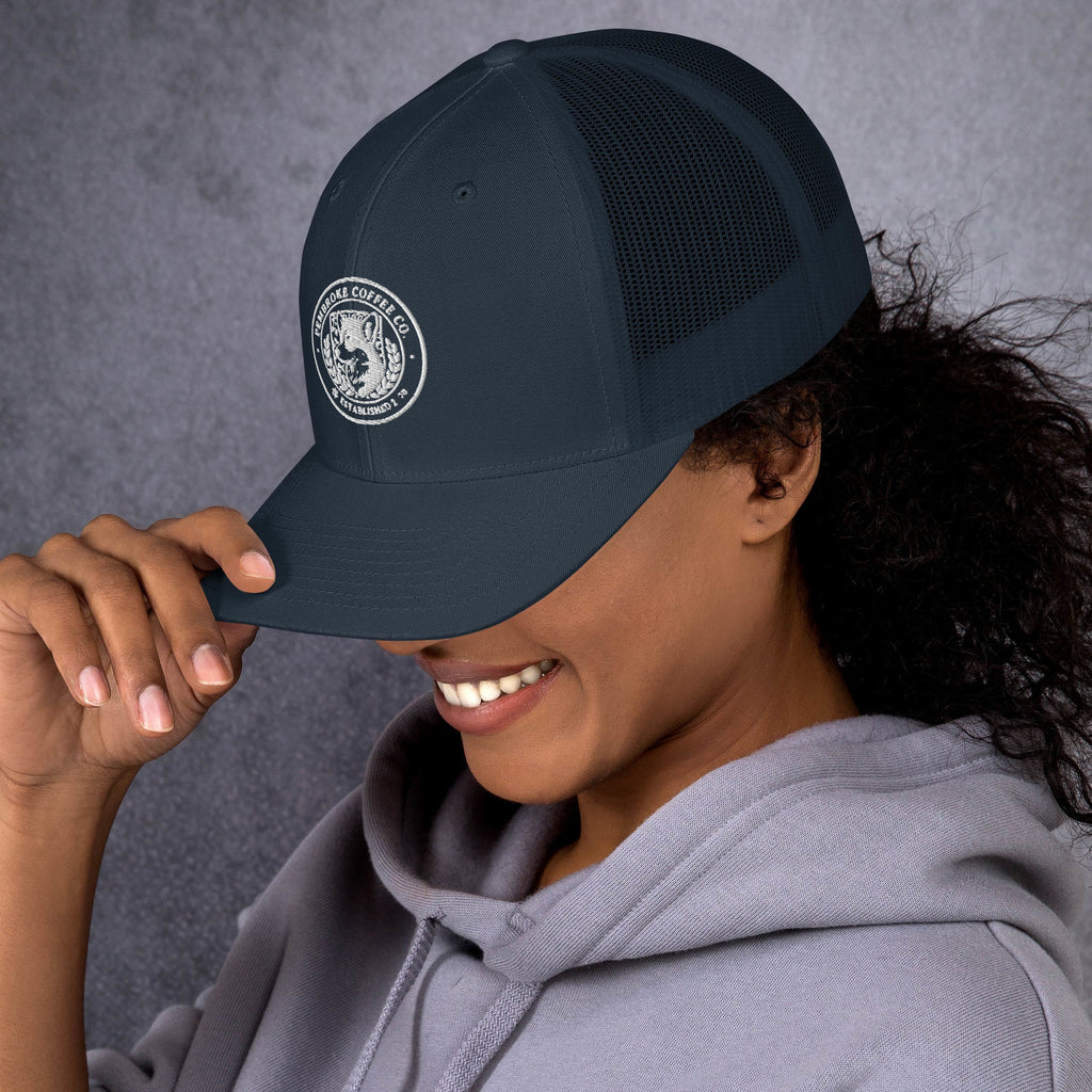 Woman wearing a dark trucker cap with mesh back, smiling, showcasing classic style and comfort.