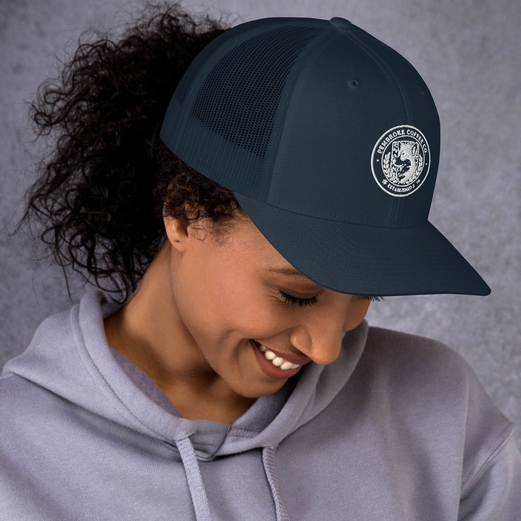 Woman wearing a Trucker Cap with a mesh back and logo, smiling in a hoodie.