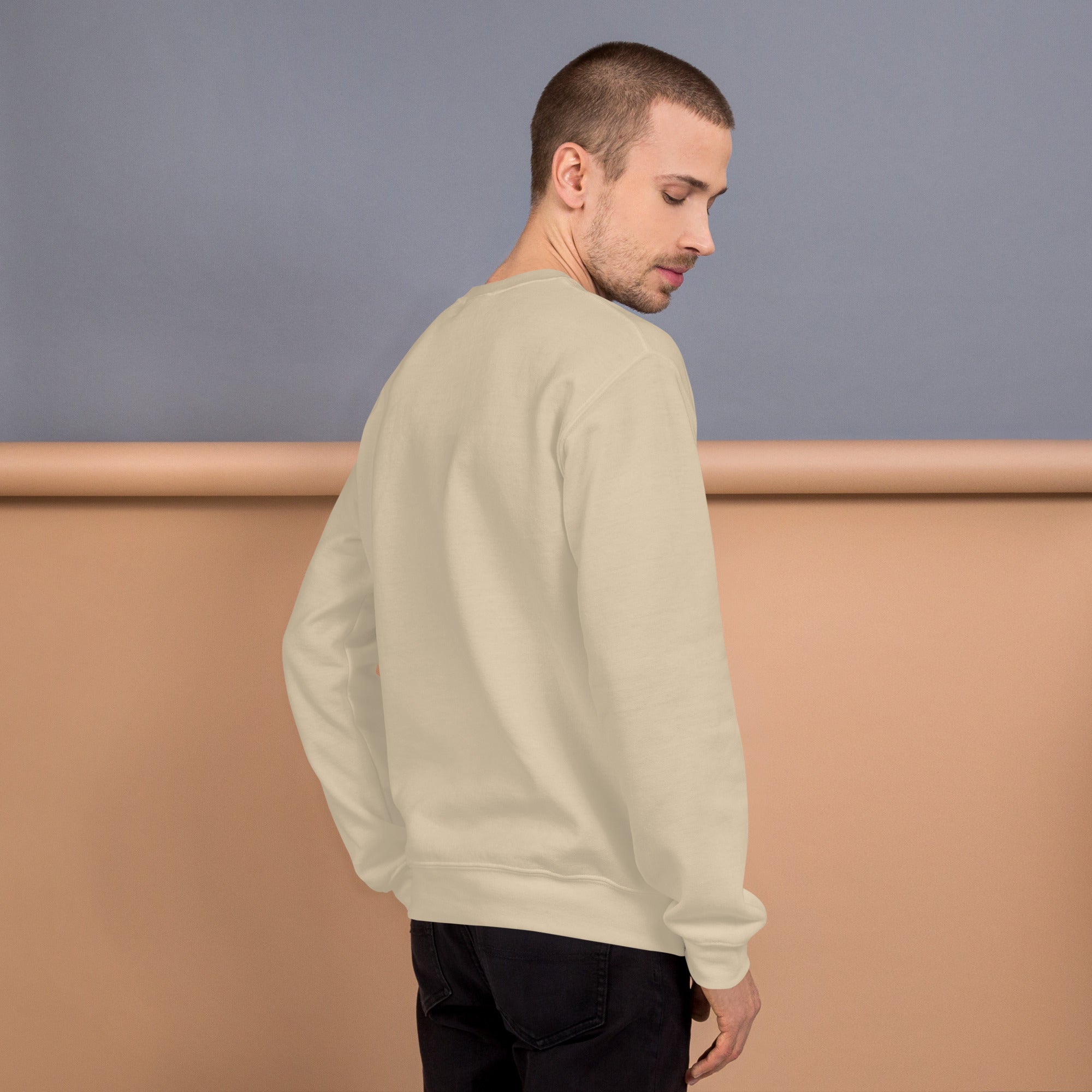 Back view of a model wearing a Unisex Sweatshirt in a soft beige color against a pastel background.