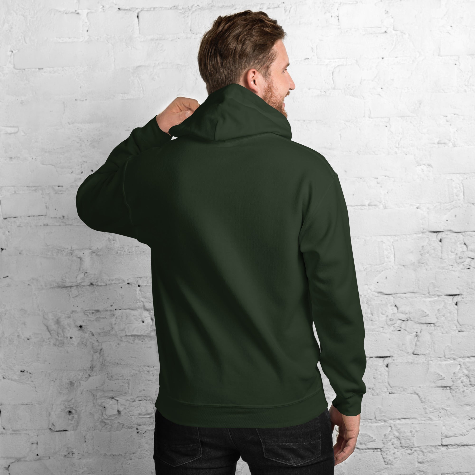 Back view of a man wearing a stylish Unisex Hoodie against a brick wall background.