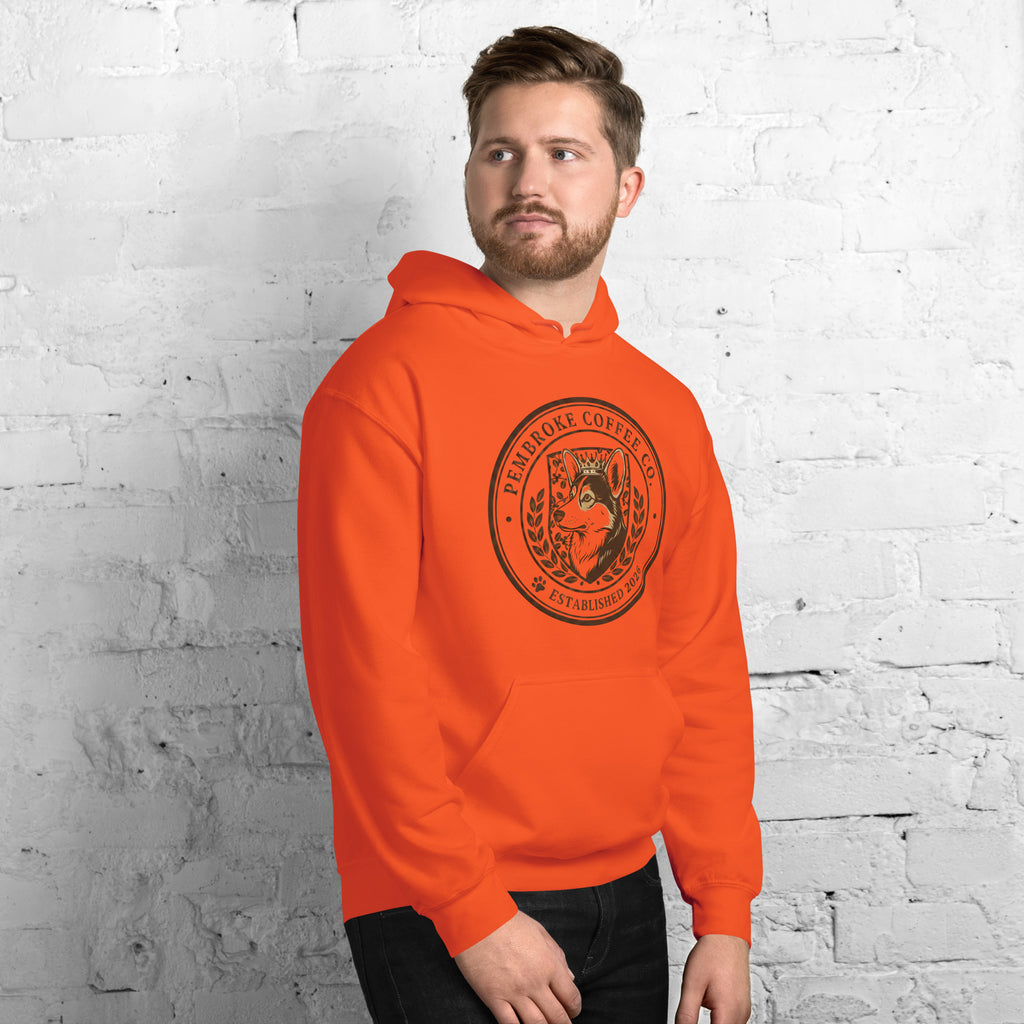 Unisex Hoodie featuring an orange design with a coffee logo on a model against a brick wall.