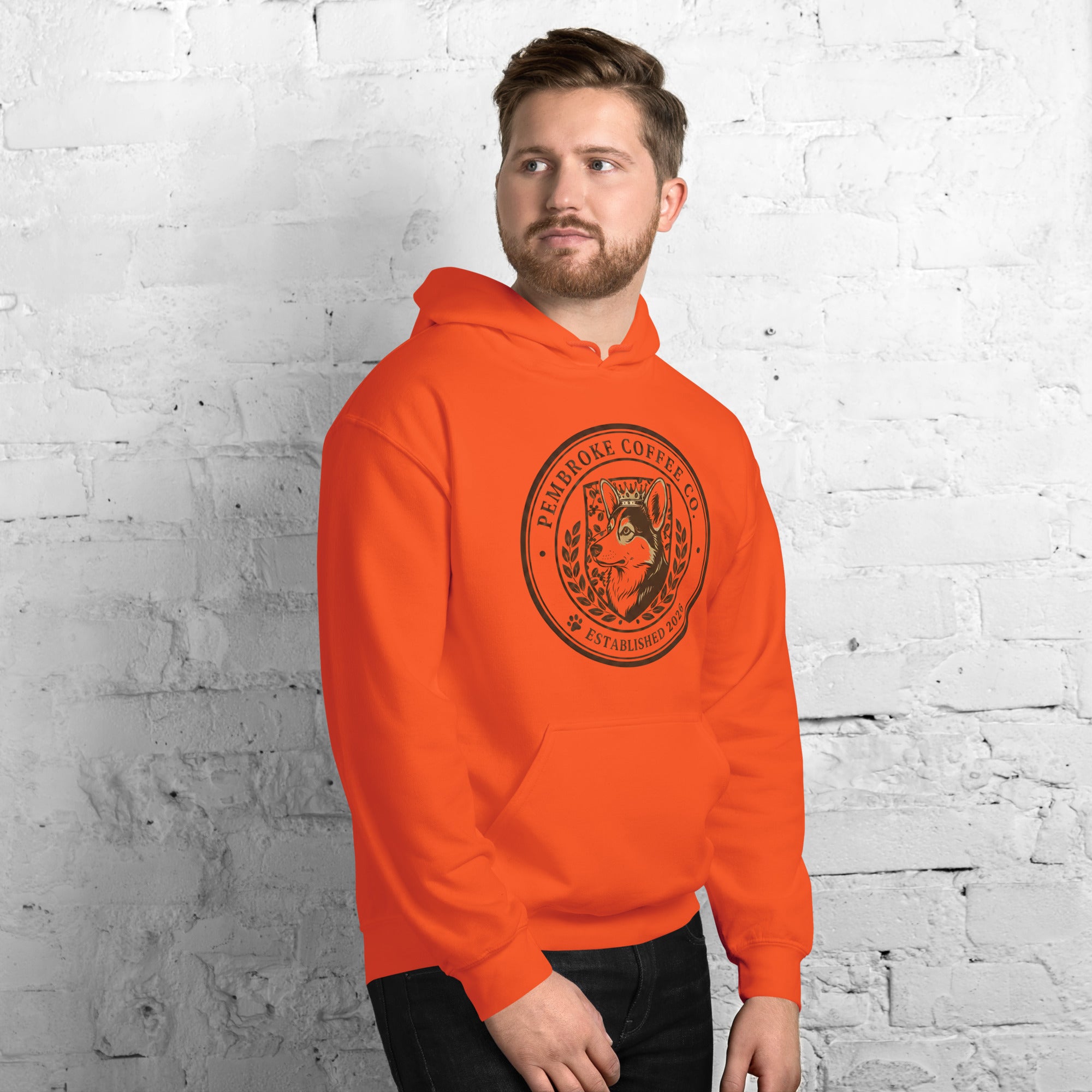 Unisex Hoodie featuring an orange design with a coffee logo on a model against a brick wall.