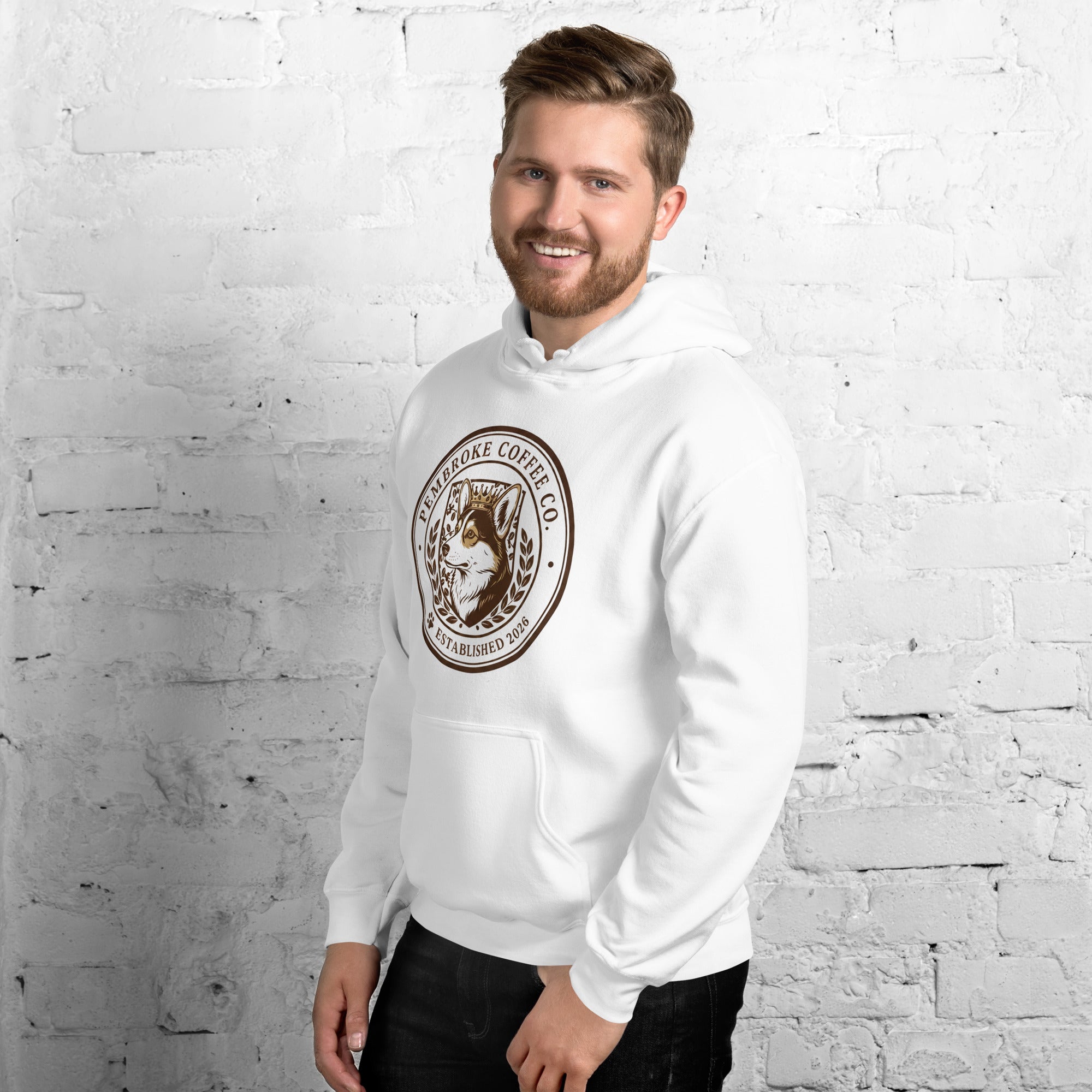 Man wearing a white Unisex Hoodie with logo, standing against a brick wall, showcasing a cozy and stylish sporty look.