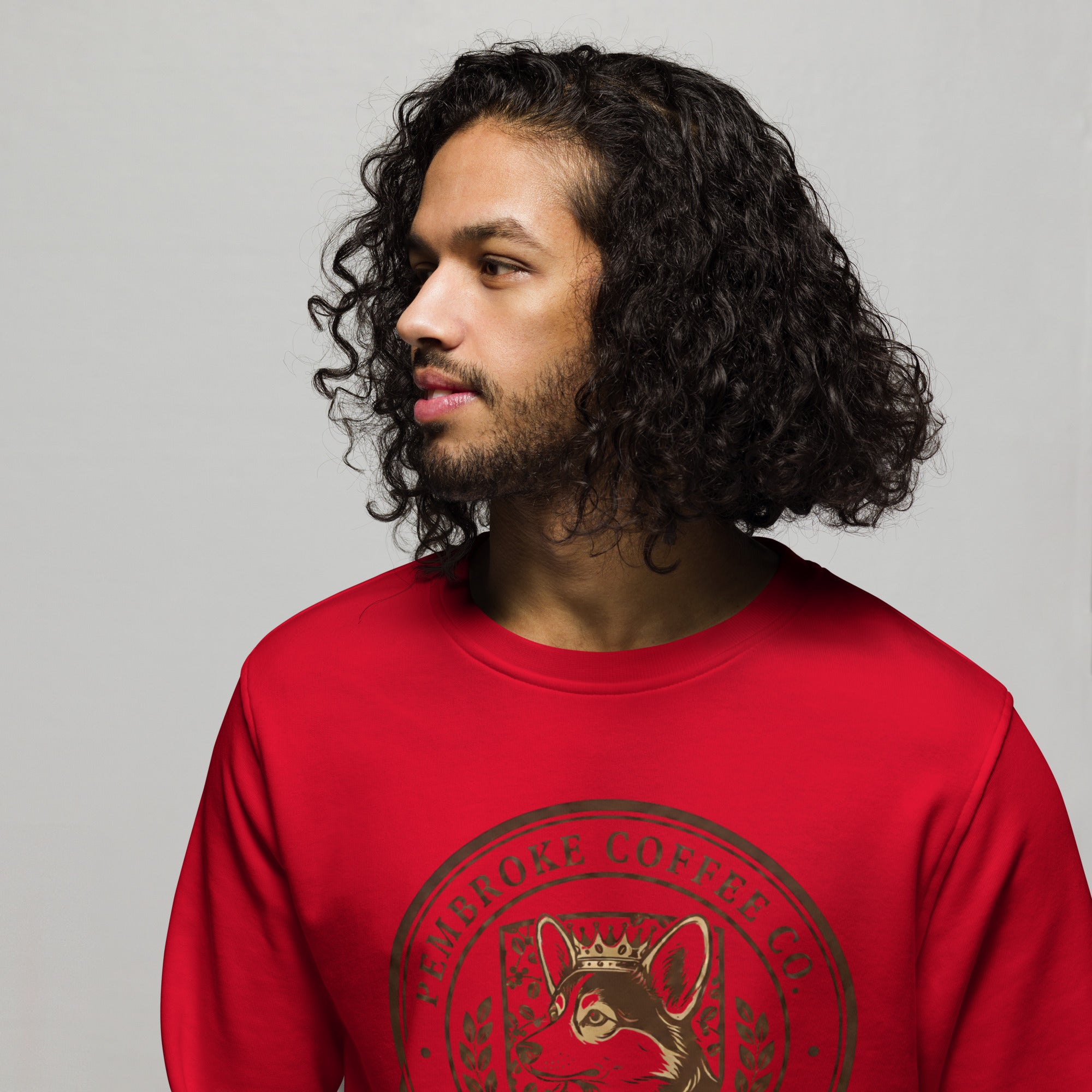 Young man wearing a red Unisex organic sweatshirt with a coffee company logo.
