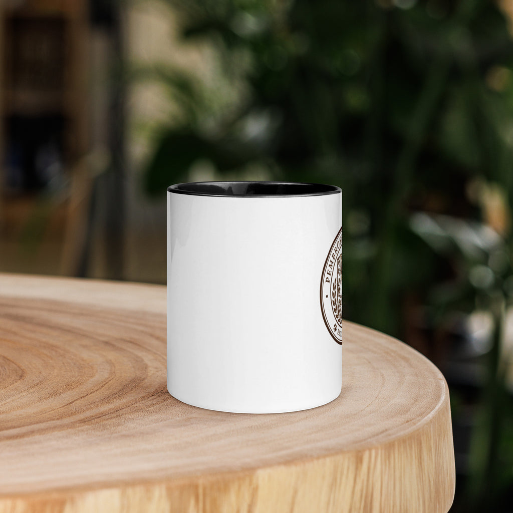 Mug with Color Inside featuring a black rim on a wooden table surrounded by greenery.